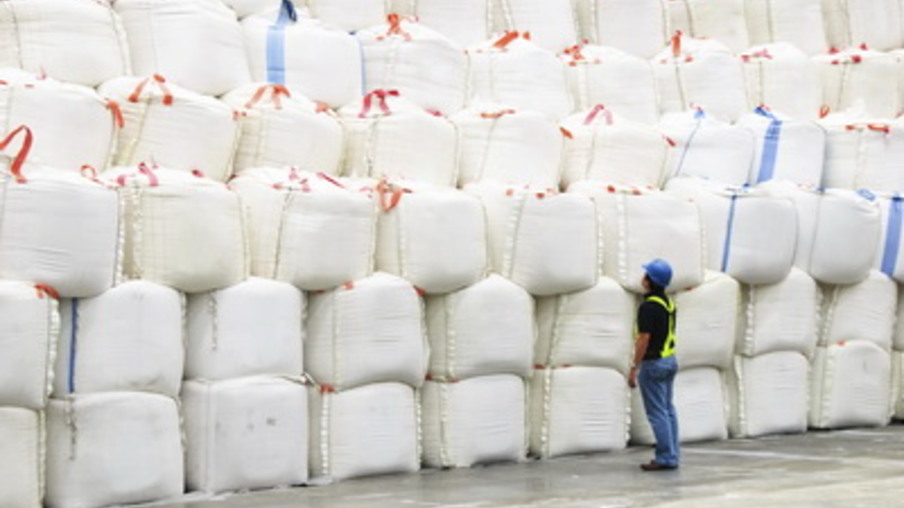 Supervisor inspecting huge sacks of sugar in a warehouse.